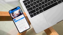 Laptop i telefon z wyświetlonym Facebookiem na szklanym stole